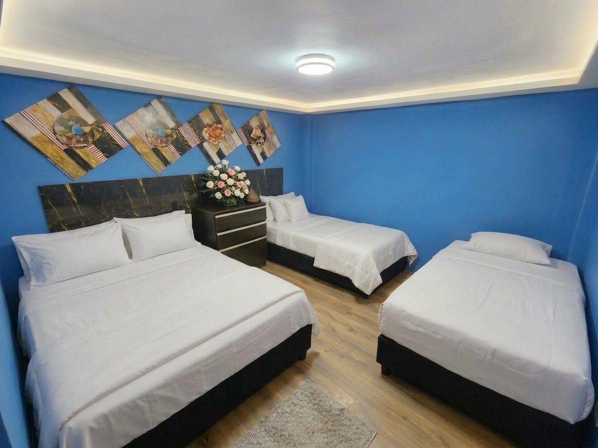 Une chambre d’hôtel avec deux lits, une table de chevet et des œuvres d’art murales.