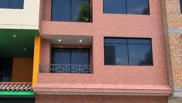Un edificio de varios pisos con techo plano, ventanas grandes y entrada protegida por una reja.