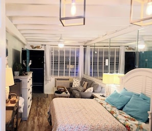 Un dormitorio con cama, cómoda, mesita de noche, ventana con persianas y ventilador de techo.