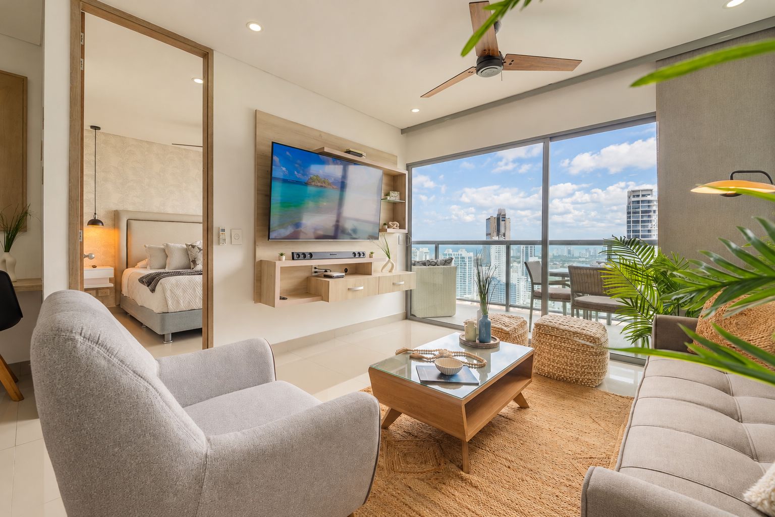 Ein modernes Wohnzimmer mit Flachbildfernseher, Deckenventilator und großem Fenster mit Blick auf die Stadt.