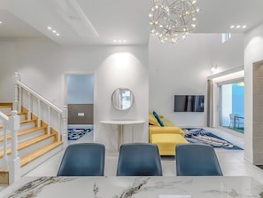 A modern living room with a staircase, a round mirror, a sofa, and a flat-screen TV. - Hian Private Pool Villa (Gyeongju)