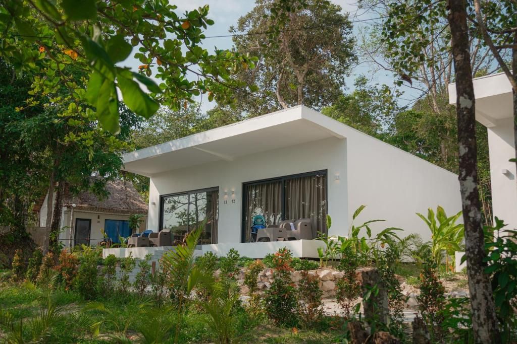 Una casa moderna con techo plano, ventanas amplias y un balcón con mobiliario exterior.
