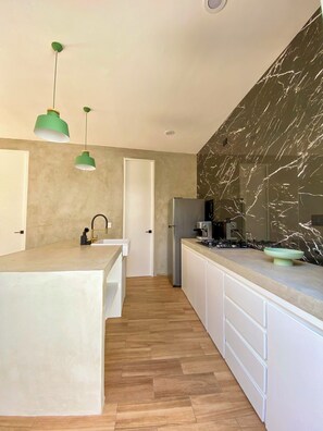 Eine moderne Küche mit Marmorfliesenspiegel, Holzboden und weißer Arbeitsplatte.