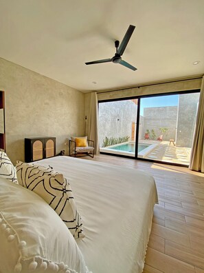 A bedroom with a large bed, a ceiling fan, a view of an outdoor swimming pool, and a sliding glass door. - New Listing (Progreso)