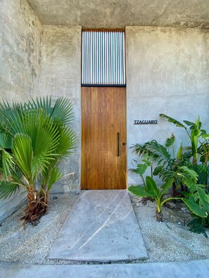 A wooden door with a metal grille, a concrete pathway leading to it, and a sign reading 'IZAGUARO' on the wall. - New Listing (Progreso)