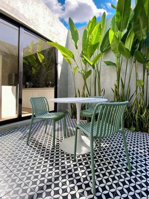 Eine Terrasse mit einem gemusterten Boden, einem Tisch und zwei Stühlen.