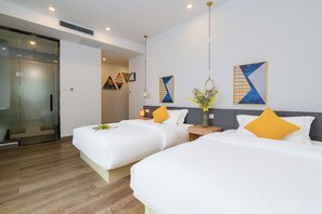 Een hotelkamer met twee bedden, een nachtkastje met een lamp en een kunstwerk aan de muur.