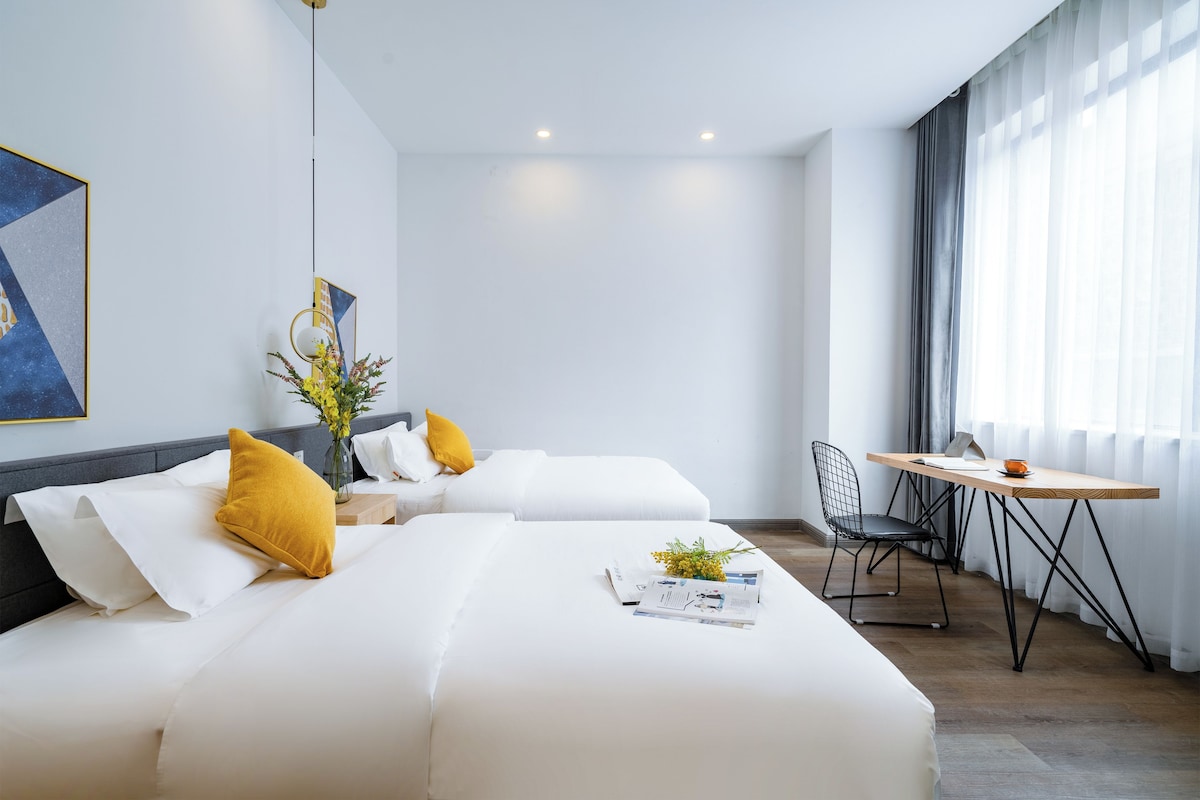 Een moderne hotelkamer met twee bedden, een eettafel en een stoel.