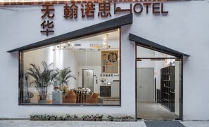 A hotel entrance with a large glass window, a reception desk, and a signboard. - xianwuhuahannuosijiudian (Xi'an)