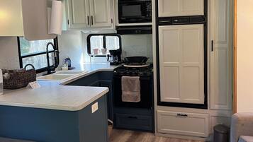 A compact kitchen with a microwave, stove, and cabinets.