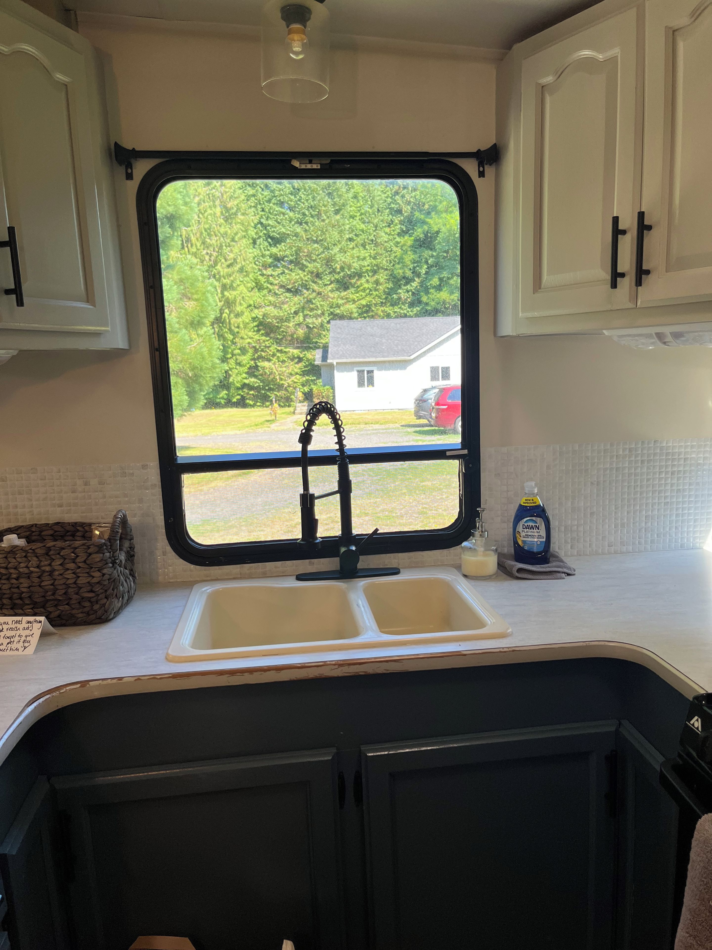 A kitchen with a window, a sink, and cabinets.