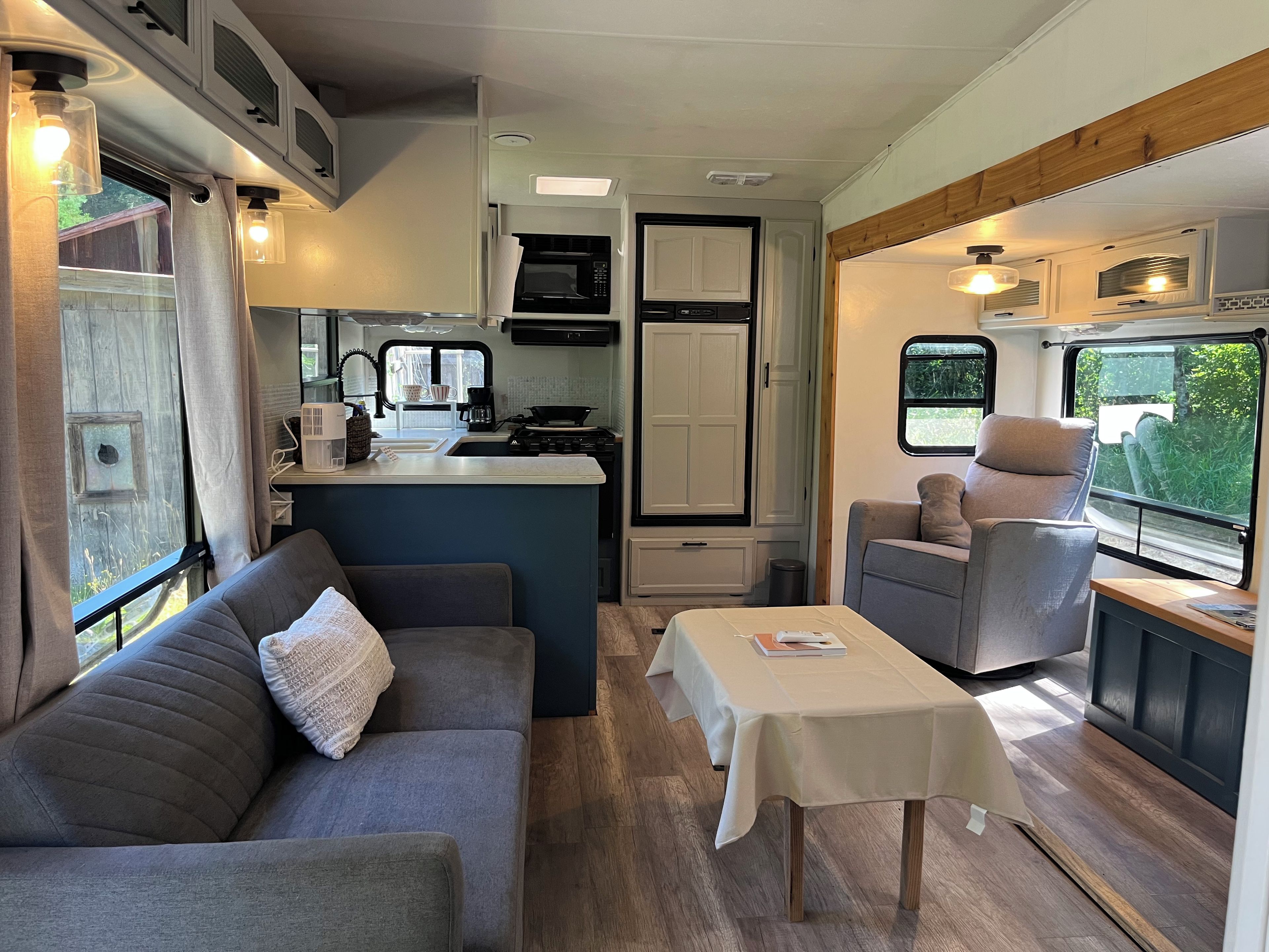 Interior d'una autocaravana compacta amb cuina americana, sofà, taula i finestra.