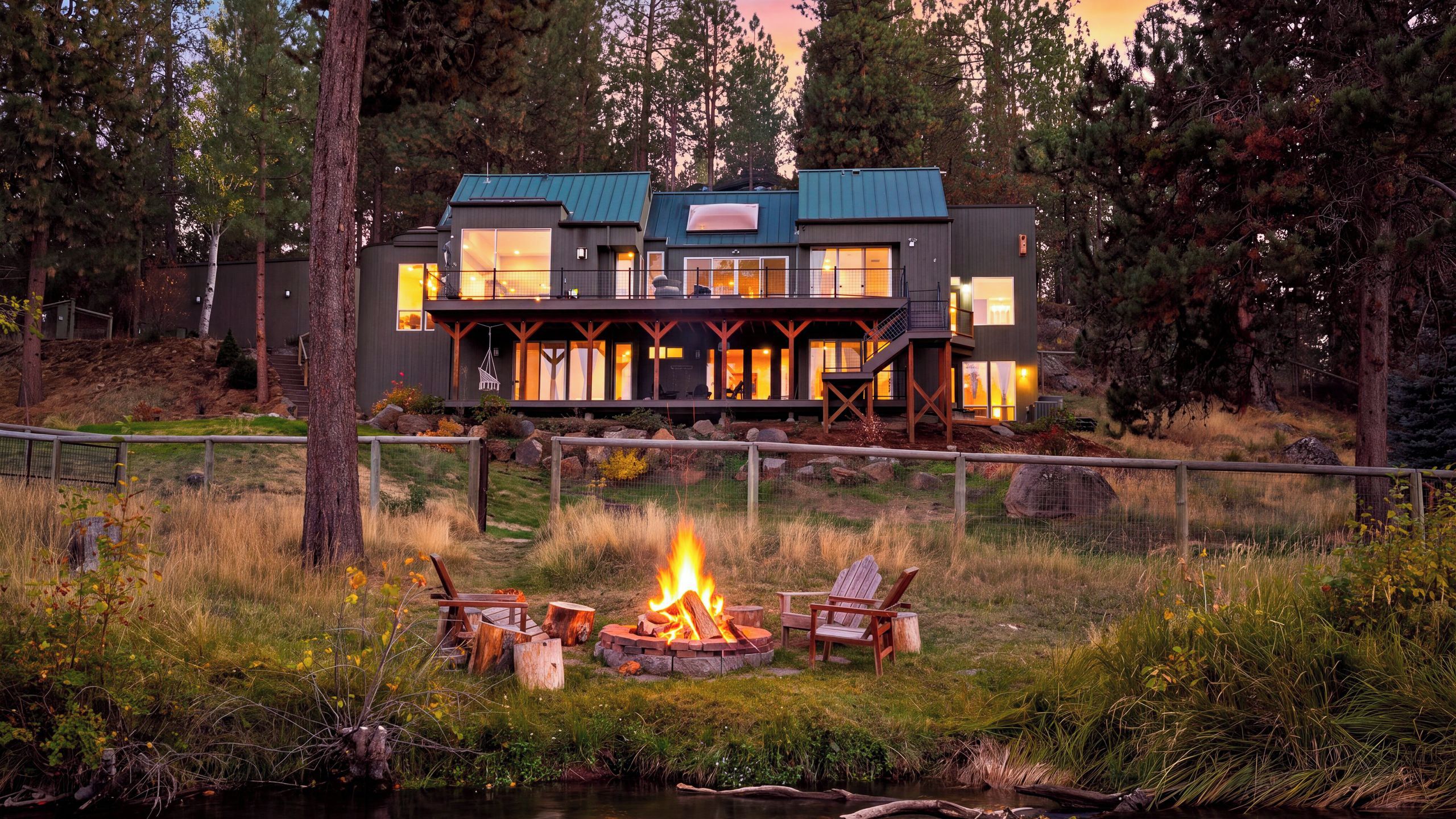 A modern two-story house with a deck and a fire pit in the front yard.