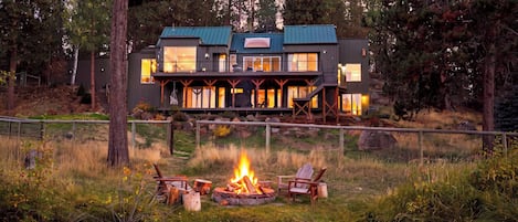 A modern two-story house with a deck and a fire pit in the front yard.