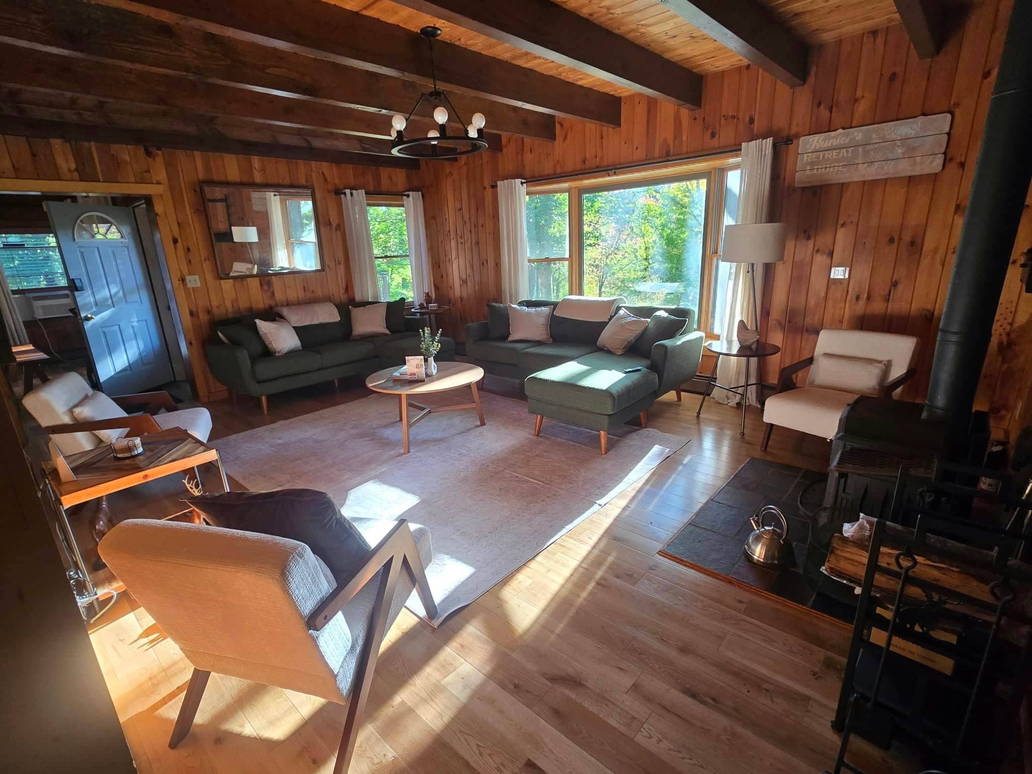 Een knus houten huisje met een bank, stoelen, een tafel en een open haard.