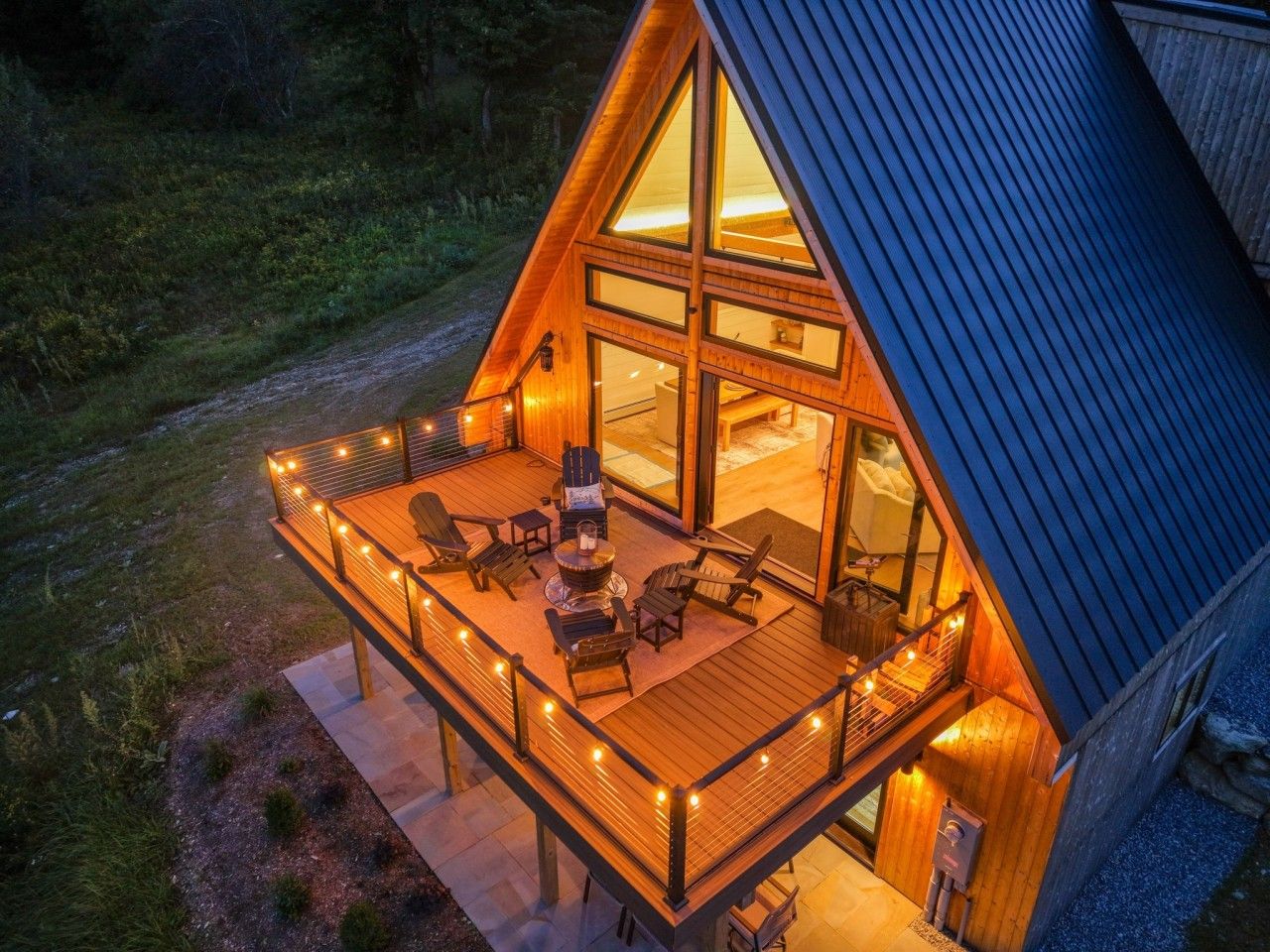 A wooden deck with outdoor seating and a fire pit, surrounded by a glass-enclosed structure.
