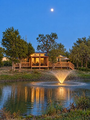 Una cabaña junto al lago con un muelle y una fuente.