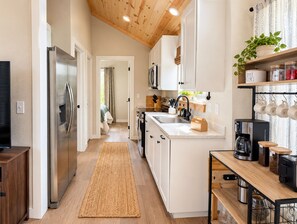 Una cocina moderna con un refrigerador de acero inoxidable, una cafetera y una encimera de madera.