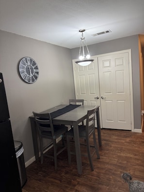 Un comedor con una mesa, sillas, un reloj de pared y una puerta.