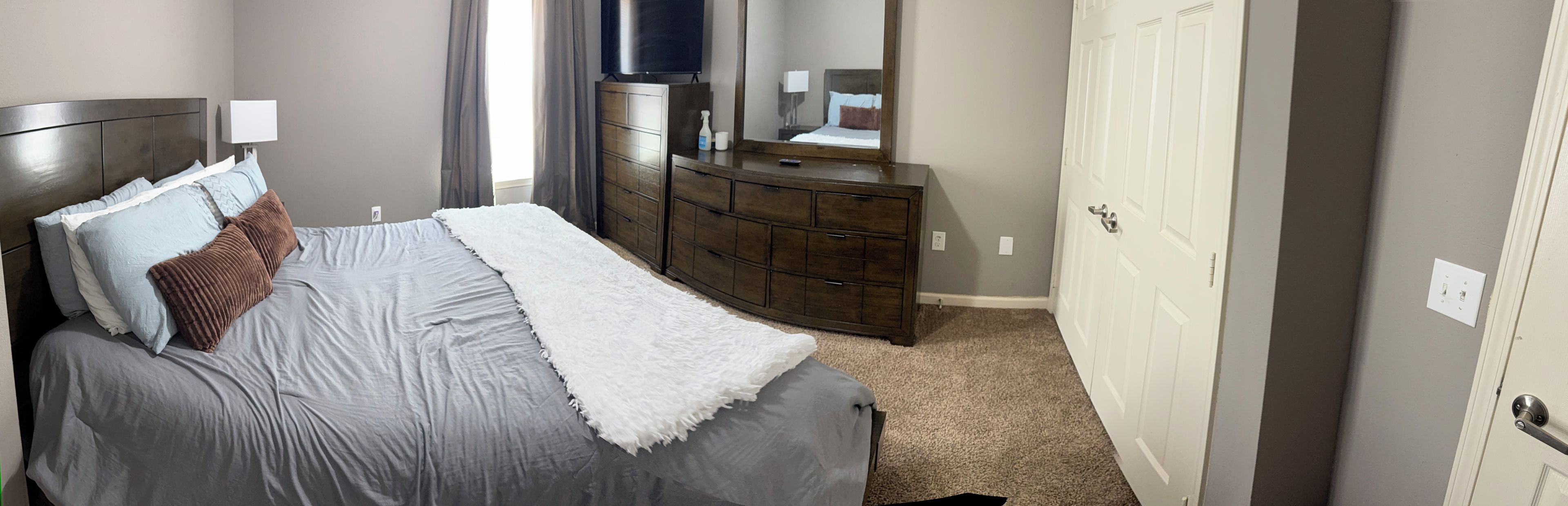A bedroom with a bed, dresser, and a television.