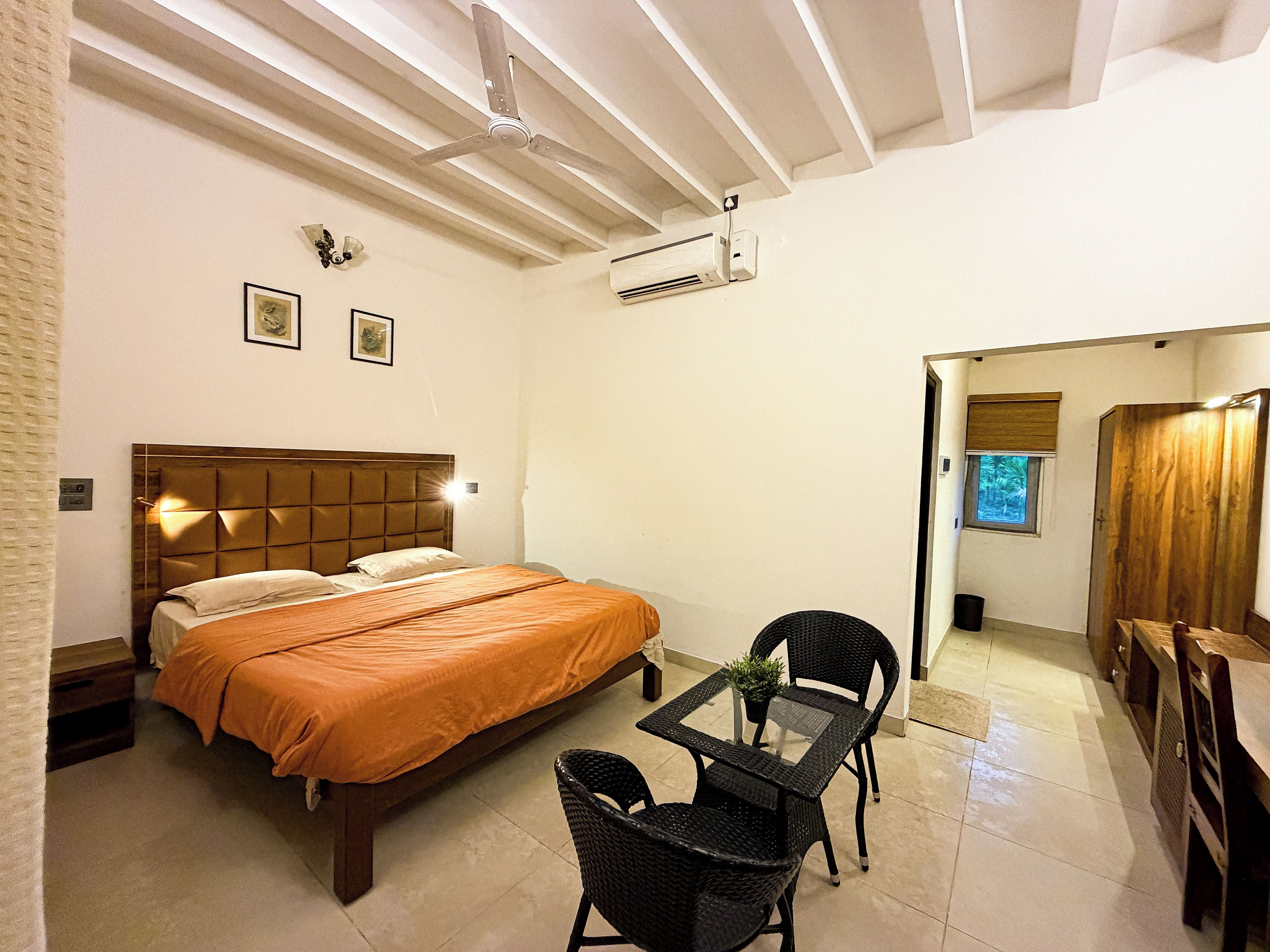 Habitación de hotel con una cama, una mesa con sillas, un ventilador de techo y un equipo de aire acondicionado.