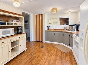 A kitchen with wooden cabinets, a microwave, a coffee maker, and a refrigerator.