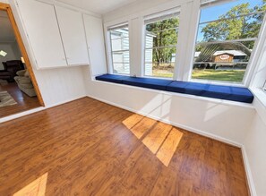 Ein Zimmer mit großem Fenster, Holzboden und einer integrierten Sitzbank.