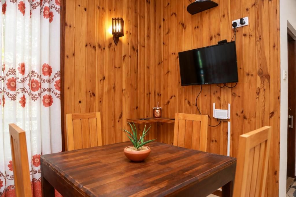A wooden-paneled room with a television mounted on the wall, a table with a potted plant, and a chair.