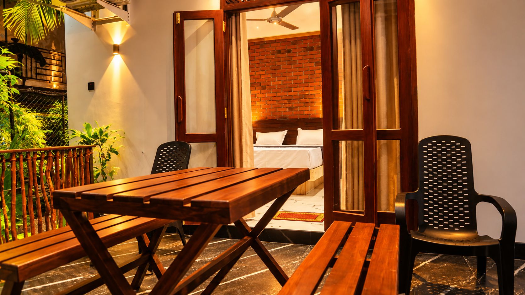 A wooden table and chairs in a room with a brick wall and a balcony.