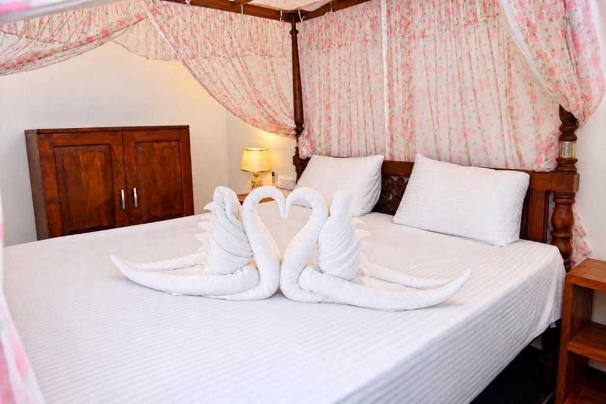 Una habitación de hotel con una cama, un armario de madera y una mesita de noche con lámpara.