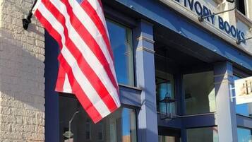 A storefront with a sign reading 'Horn & Ivory Books' and an American flag.