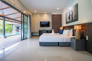 A modern bedroom with a large bed, a flat-screen TV, a desk, and a painting on the wall. - Secluded 3BR Pool Villa near Nai Harn Rawai (Tambon Rawai)