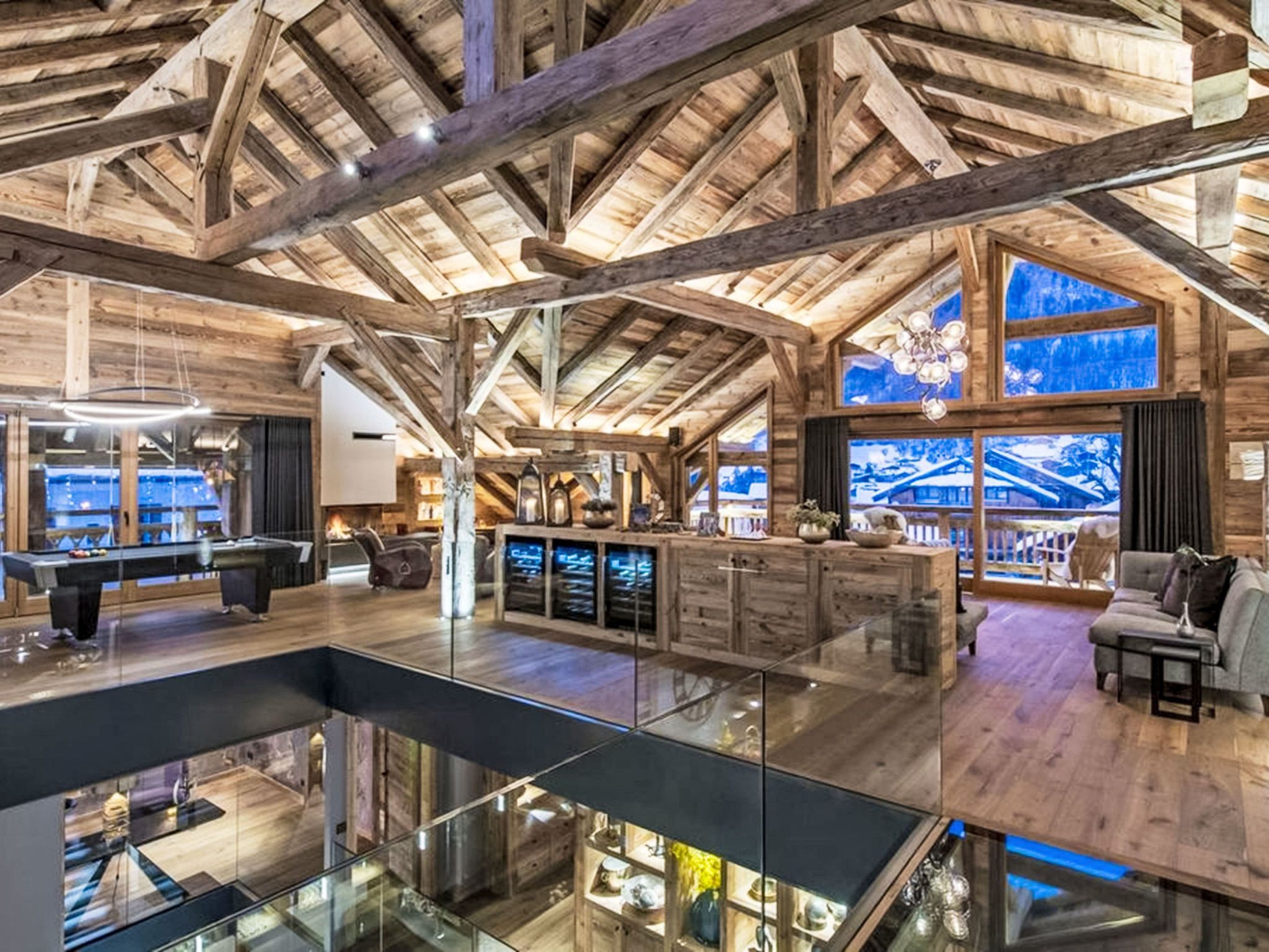 A spacious interior with a high ceiling, wooden beams, a pool table, and a bar area.