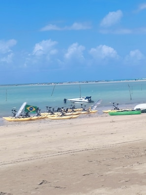 A beach with kayaks and a boat, clear skies, and calm water. - New Listing (Maragogi)