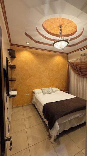 Ein Schlafzimmer mit einem Bett, einer Deckenleuchte und einem an der Wand befestigten Regal.