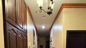 A hallway with a chandelier, wooden cabinets, and a door.
