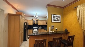 A kitchen with wooden cabinets, a refrigerator, a stove, and a dining area with chairs. - New Listing (Puerto Cortés)