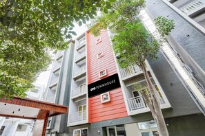 A multi-story building with balconies and a sign reading 'OYO TOWNHOUSE'.