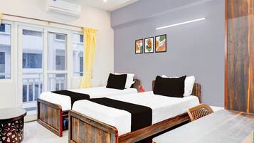 A hotel room with two beds, a balcony, a dining table, and a wall-mounted air conditioner.