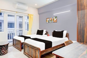 Ein Hotelzimmer mit zwei Betten, einem Balkon, einem Esstisch und einer Wandklimaanlage.