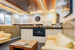 A reception area with a marble wall, a clock, a reception desk, and two sofas.