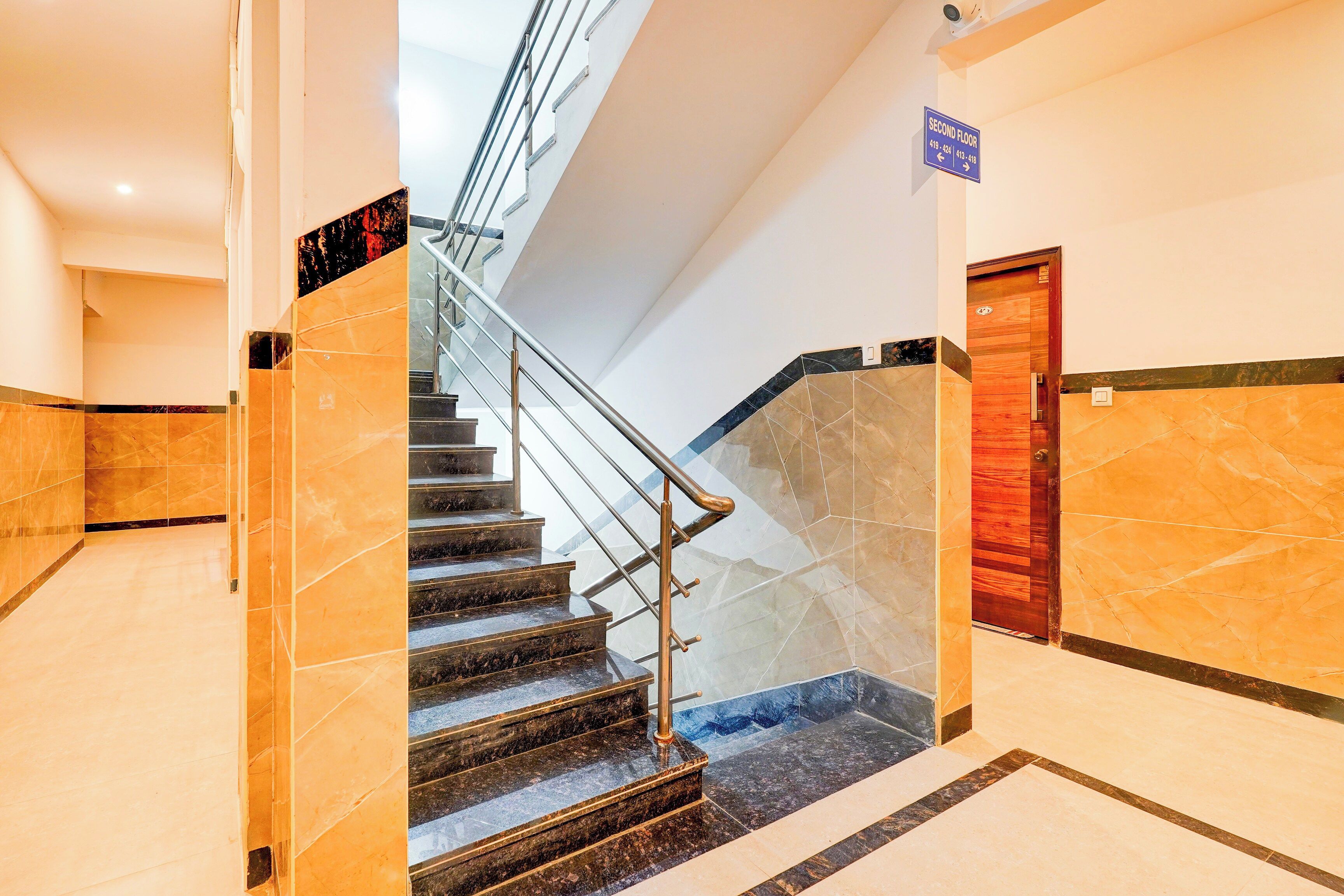 A hotel interior with a marble staircase, a second-floor sign, and a wooden door.