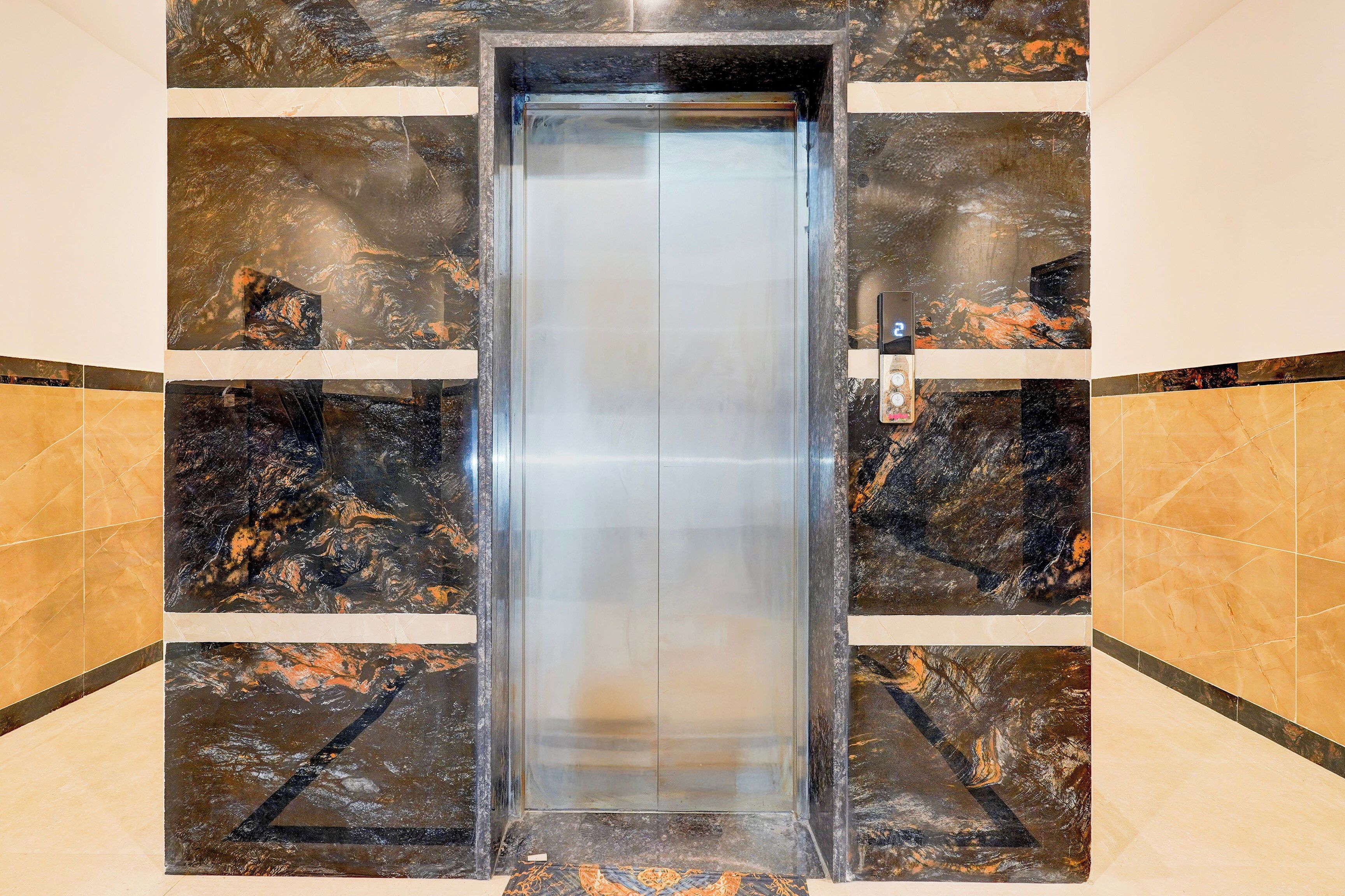 Un ascensor con revestimiento metálico y paredes de mármol.