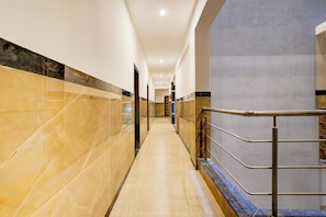 A corridor with marble walls and a metal railing. - Townhouse Jeevith Gardens Residency (Bangalore)