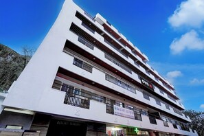 Un edificio de varios pisos con balcones y una farmacia en la planta baja.