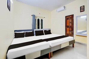 A hotel room with a large bed, a wardrobe, an air conditioning unit, and a door with decorative paneling. - Hotel O Bluestar (Bangalore)