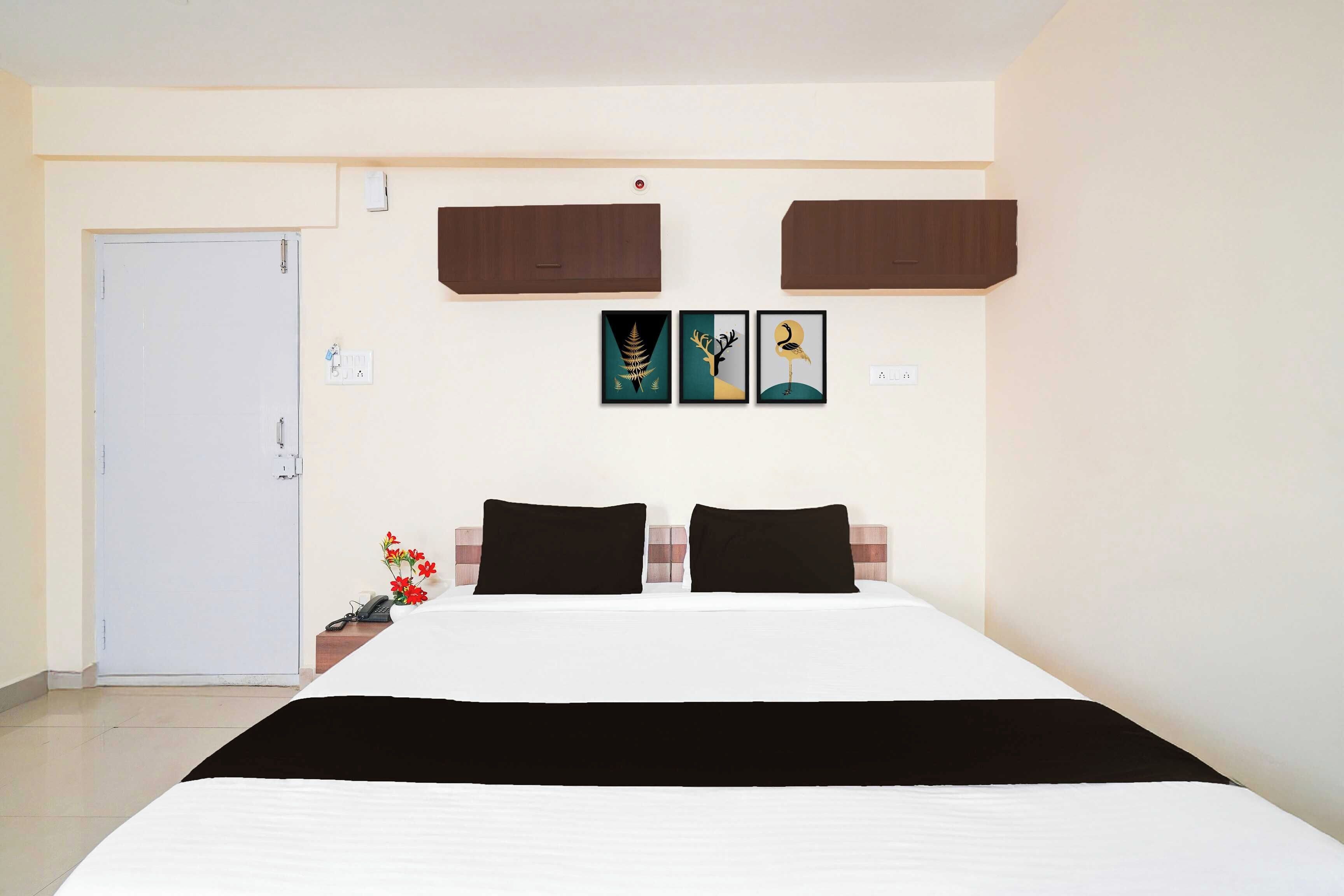 Una habitación de hotel con una cama, dos mesitas de noche, una puerta y armarios empotrados.