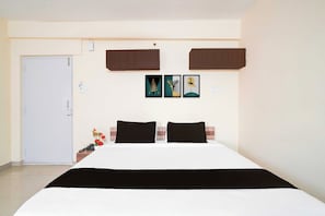 A hotel room with a bed, two nightstands, a door, and wall-mounted cabinets. - Hotel O Blueberry Hotels & Restaurant (Bangalore)