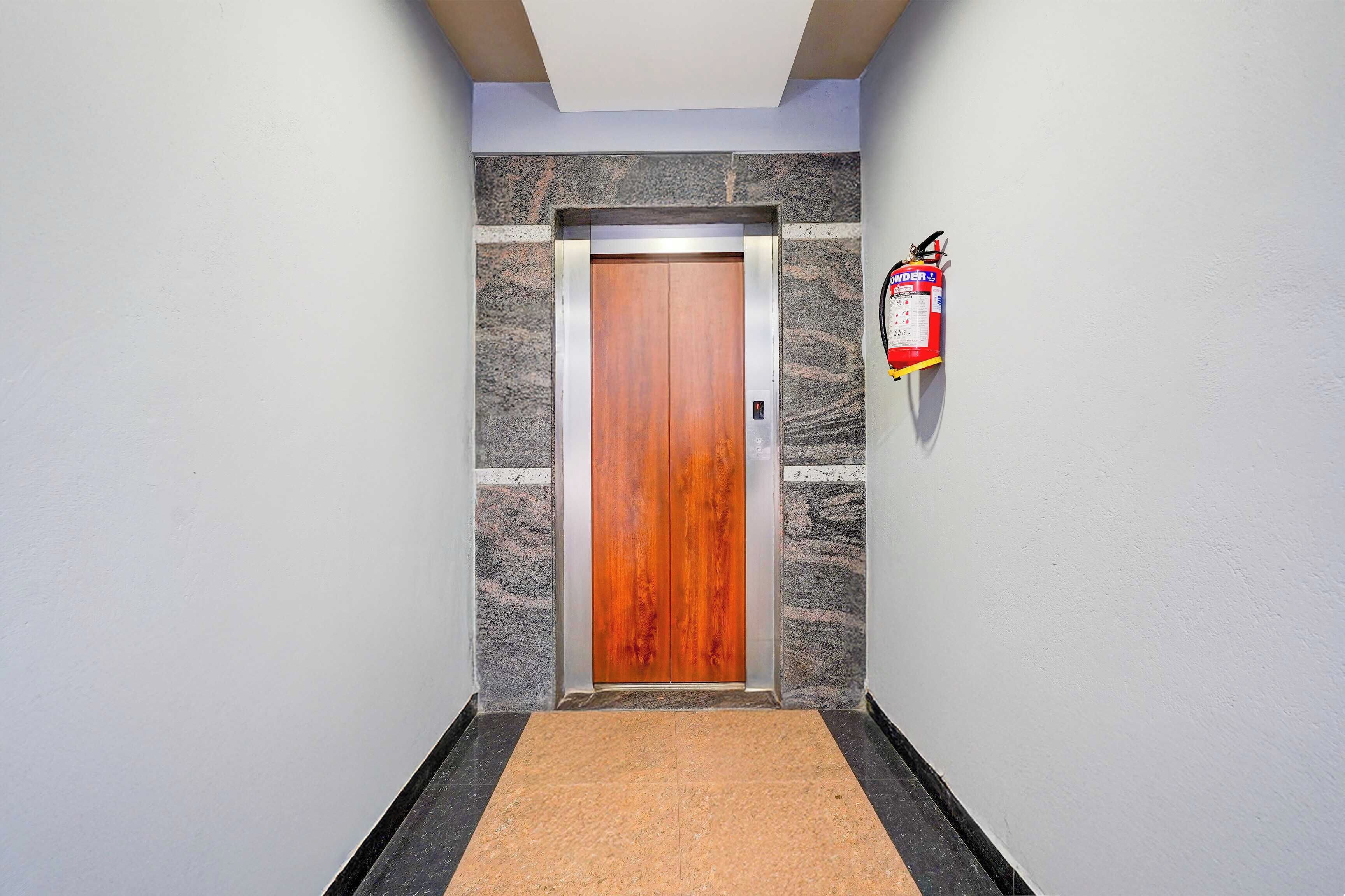 Un pasillo con una puerta de madera, un extintor en la pared y un suelo con textura.