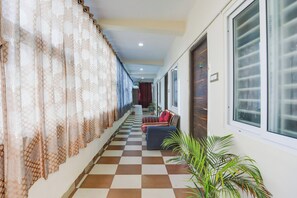 A hotel corridor with checkered flooring, a sofa with cushions, and a potted plant. - Hotel O Aqua Comforts (Bangalore)